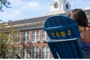 back of a blue adirondack chair with the letters TCNJ on it in yellow