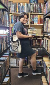 Stephanie holding a stack of books in the library.