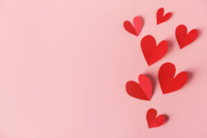red paper hearts border the right side of the frame on a pink background