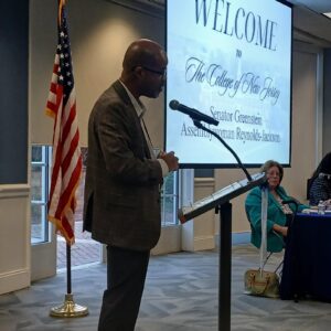 Dean Fisher Speaking at a podium from a profile perspective.